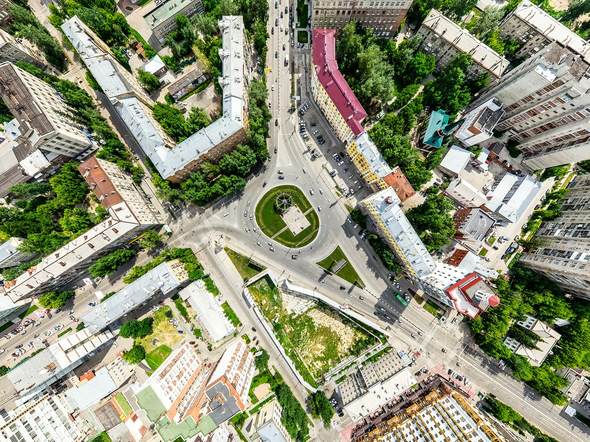 Aerial view of a circular traffic roundabout surrounded by multi-story buildings and tree-lined streets.